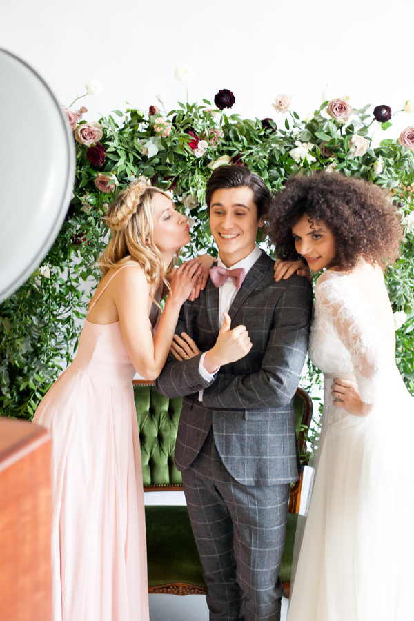 wedding party in front of flower wall using photo booth