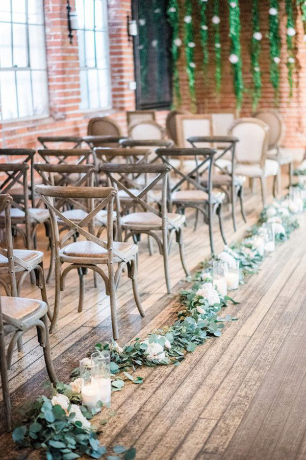 Wedding ceremony aisle lined with greenery 