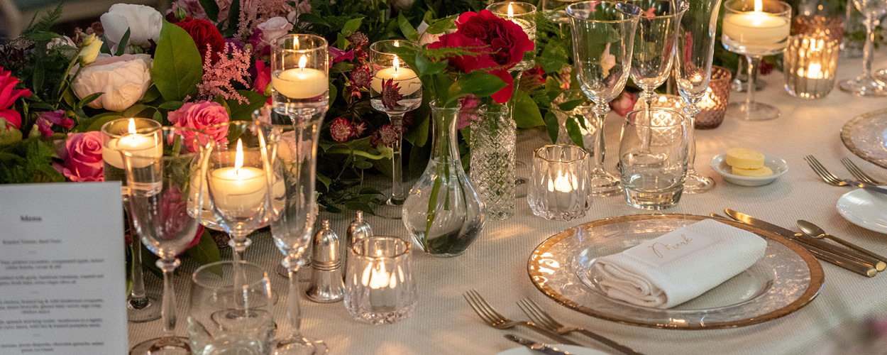 Pihk and burgundy flowers with candles on wedding top table